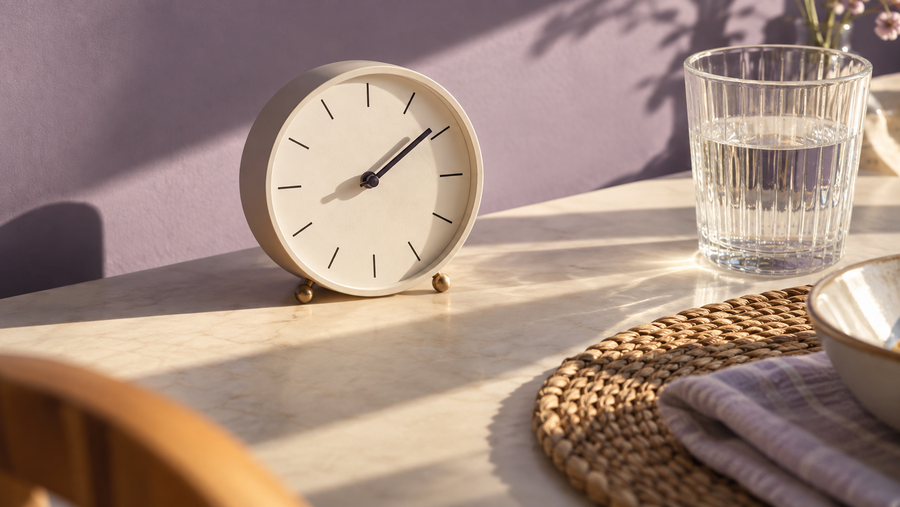 Clock and water glass beside a breakfast placemat